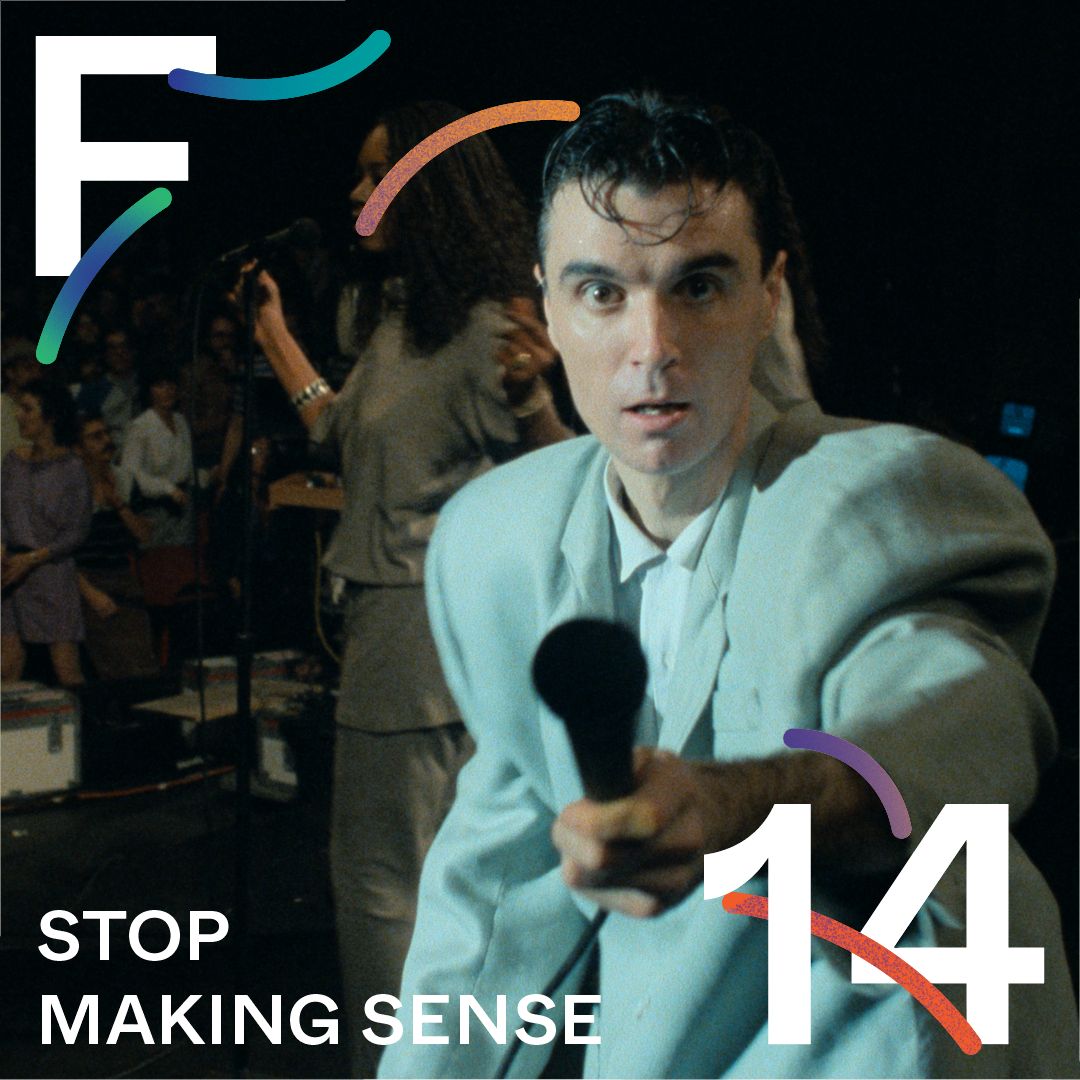 mężczyzna - brunet - w jasnym garniturze, wyciąga mikrofon w stronę widza.