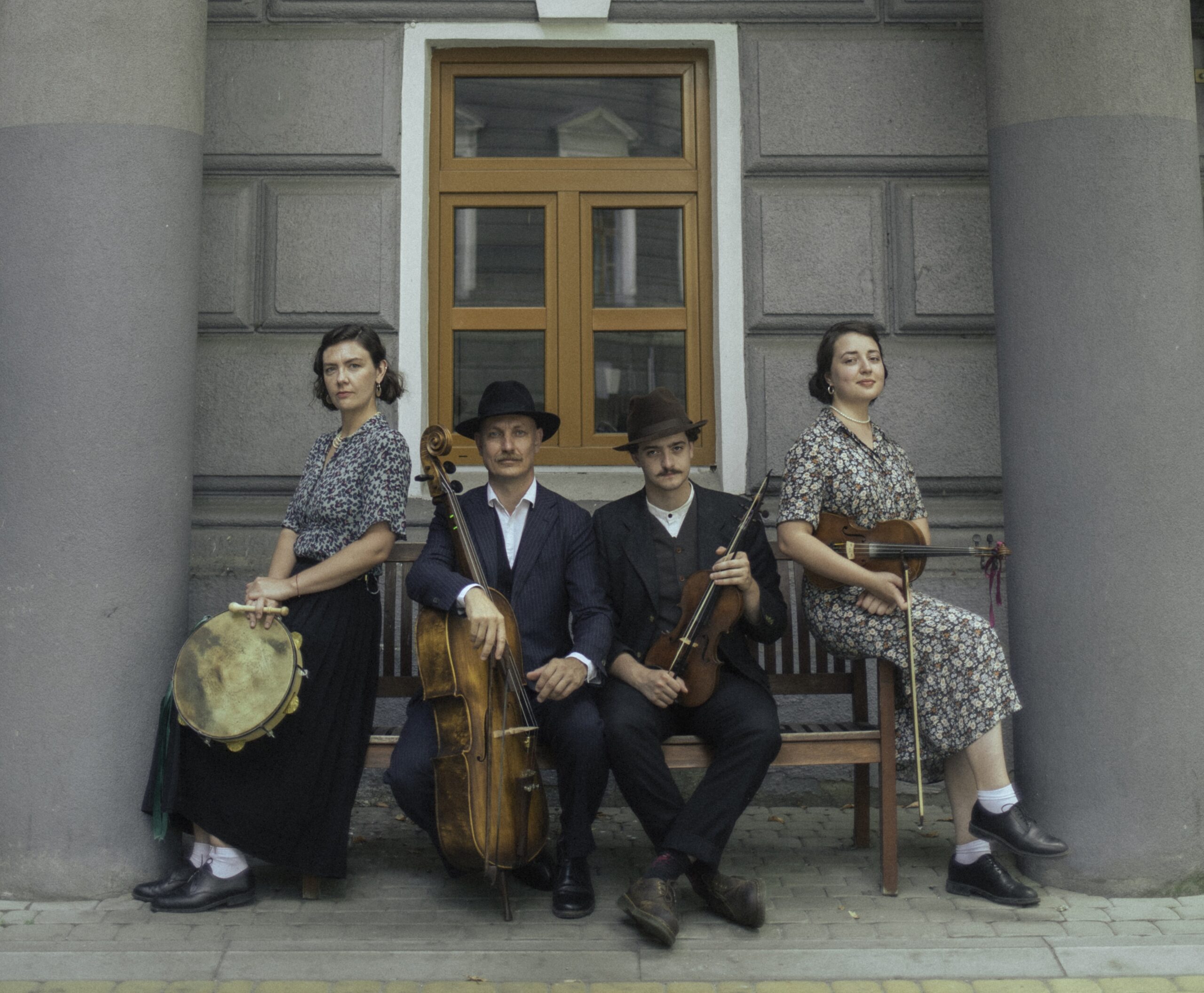 The photo shows a four-person musical group. Two women and two men with instruments in hand.