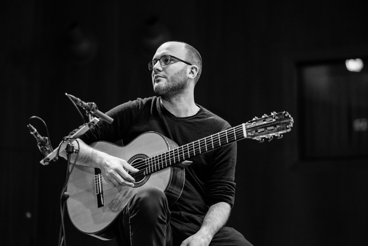 The photo shows a man playing the guitar