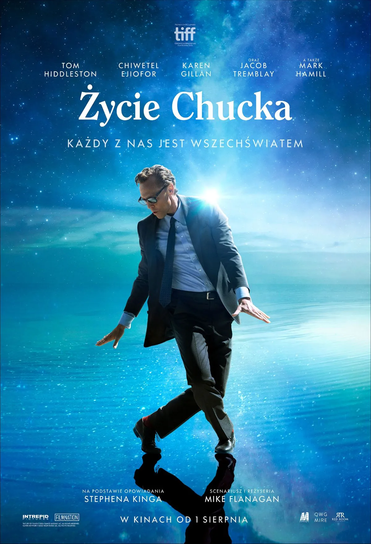 na niebieskim rozświetlonym tle mężczyzna w garniturze wykonuje taneczną pozę