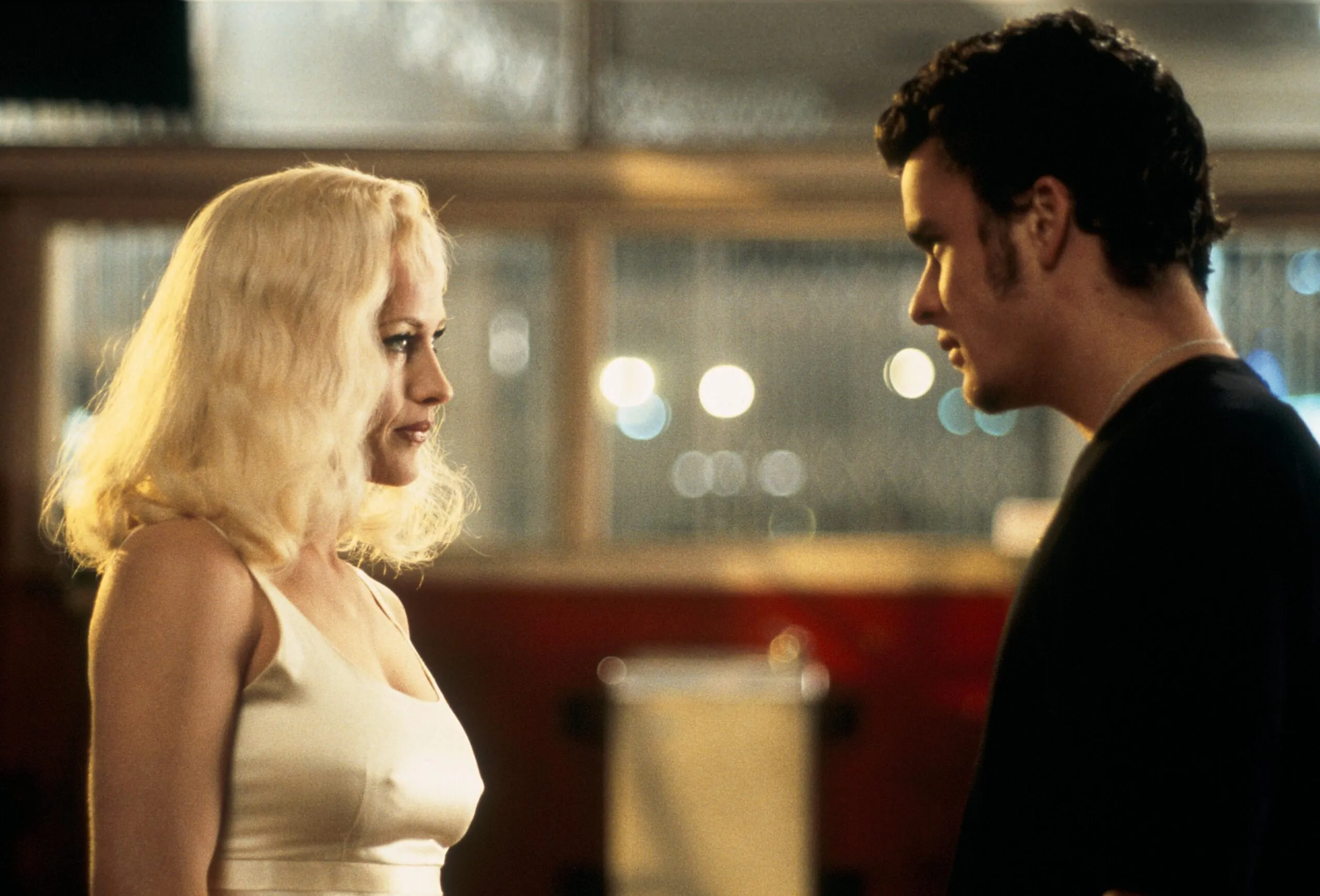 kadr z filmu. blondynka w obcisłej sukience i mężczyzna, brunet, na przeciw siebie. w tle budynek.