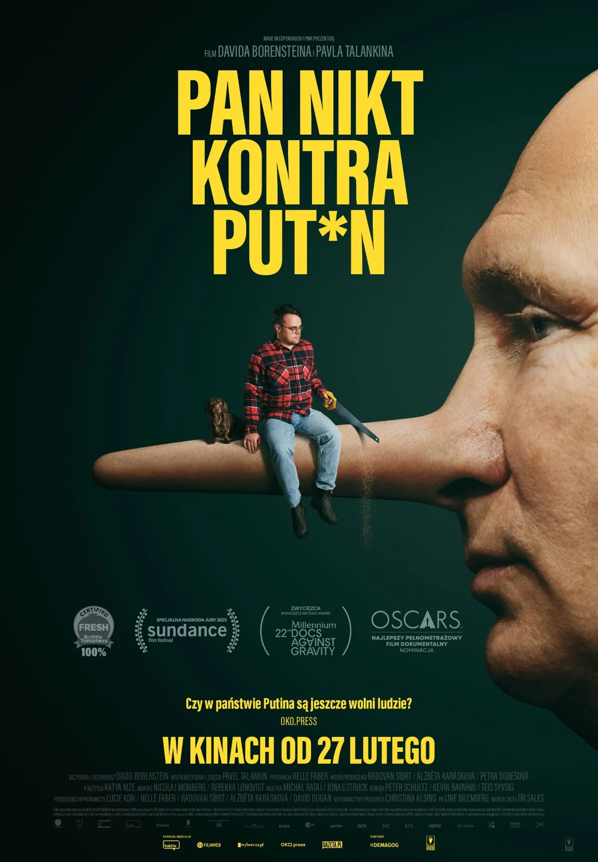 plakat - portret osoby przypominającej Putina z profilu, z nosem jak pinokio, na nosie siedzi mężczyzna w dżinsach i koszuli w kratę.