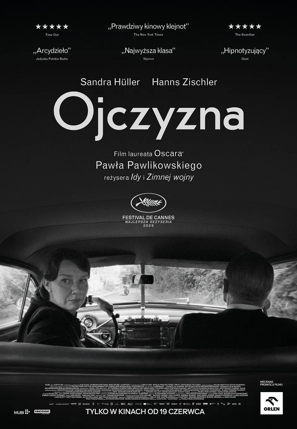 Czarno-biały plakat filmowy filmu „Ojczyzna” w reżyserii Pawła Pawlikowskiego. Na dole kadru wnętrze starego samochodu widziane z tylnego siedzenia. Kobieta prowadząca auto odwraca głowę w stronę widza, obok siedzi mężczyzna pokazany od tyłu. Nad nimi duży biały tytuł „Ojczyzna”, a wyżej nazwiska aktorów Sandry Hüller i Hannsa Zischlera. U góry znajdują się cytaty recenzji i oceny gwiazdkowe. Plakat utrzymany jest w minimalistycznej, mrocznej estetyce, z dominacją czerni i szarości. Na dole informacja o nagrodzie za reżyserię w Cannes oraz data premiery kinowej: „Tylko w kinach od 19 czerwca”. Bo przecież współczesne kino artystyczne nie może obyć się bez czerni, ciszy i ludzi patrzących przez ramię z egzystencjalnym niepokojem.